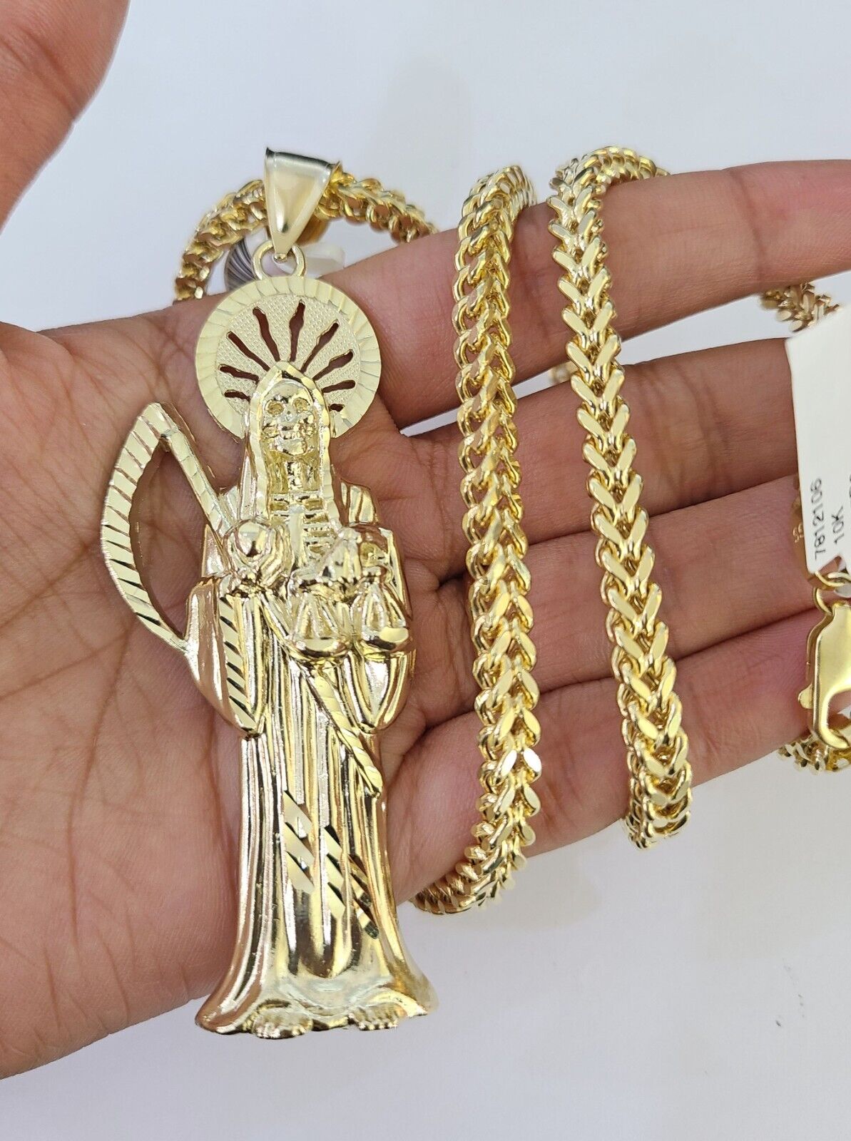 Flat lay display of Reva Jeweler 10K yellow gold Saint Reaper necklace set