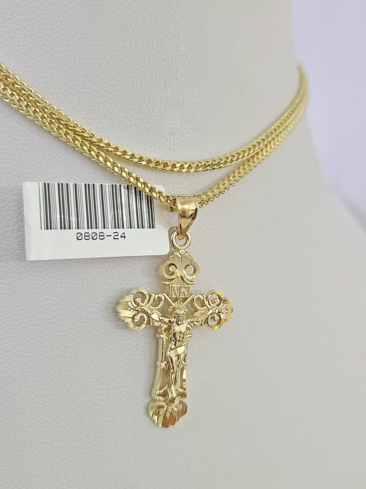 Close-up of 10K yellow gold Jesus cross pendant on Franco chain necklace